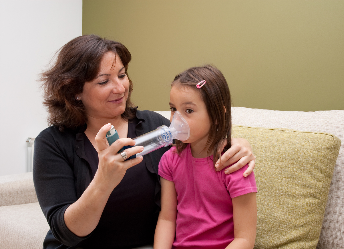 mother using inhaler with her asthmatic daughter